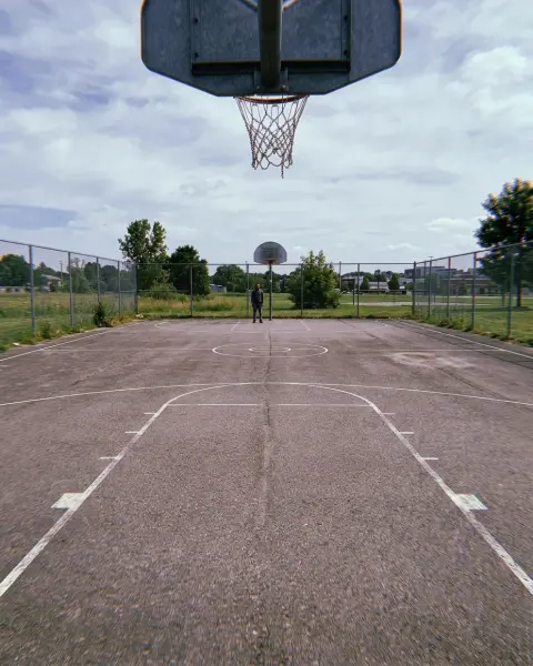 Photo to skip: a person standing far away on an empty basketball court
