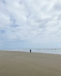 Photo to skip: a person standing far away on a beach, face too small to see